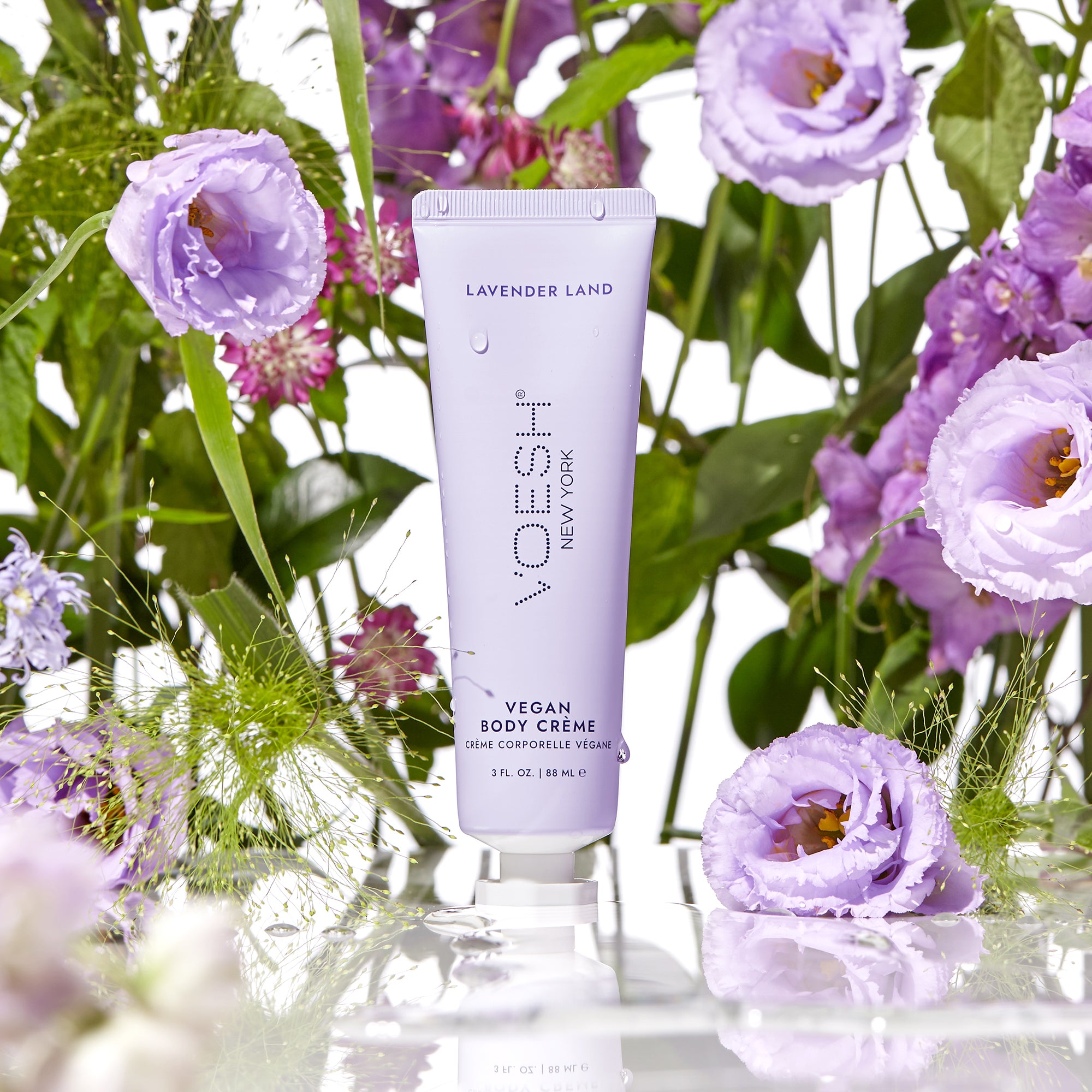Vegan Body Crème Lavender Land in front of purple flowers and green leaves.